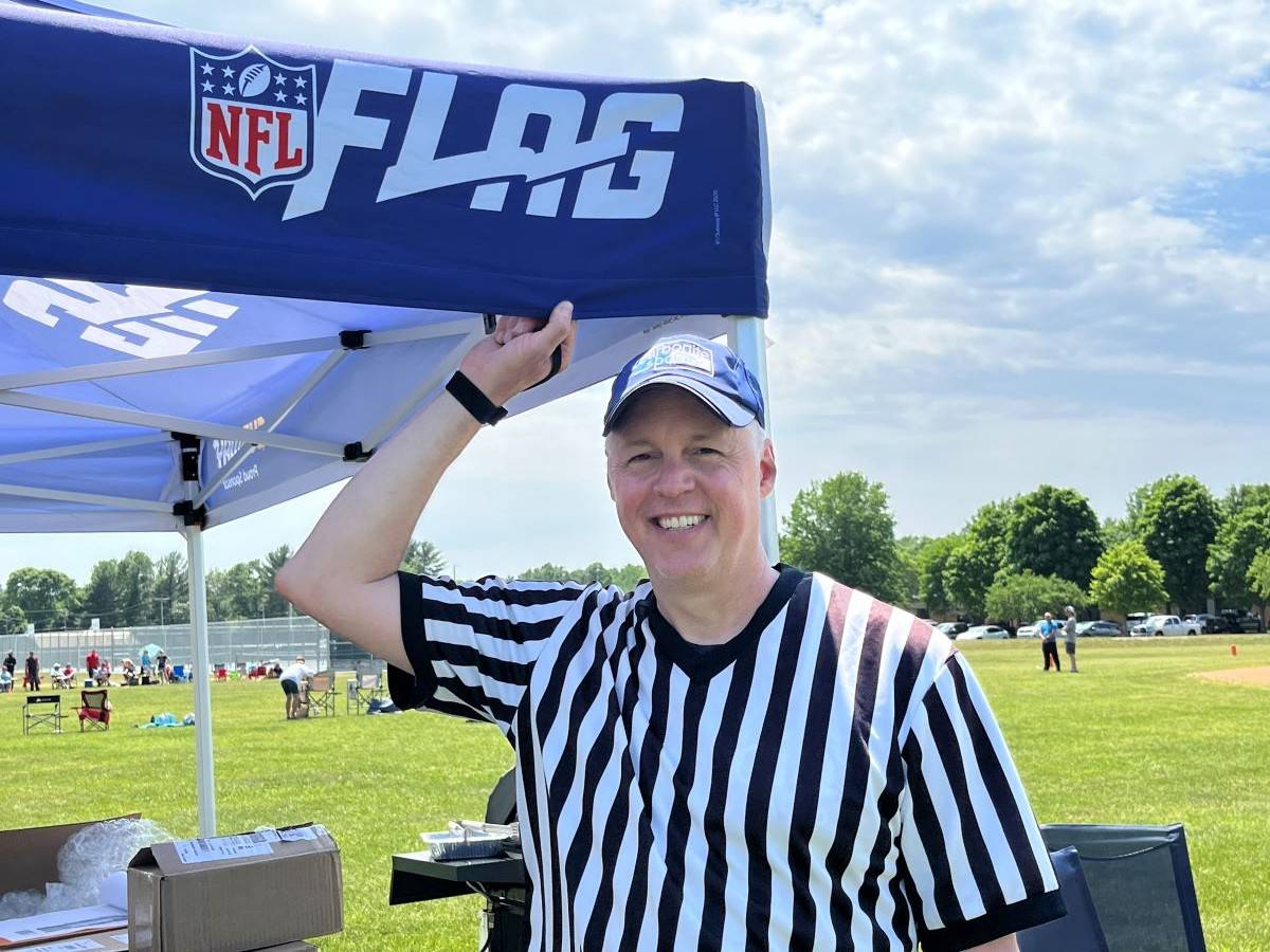 Cory wearing a black and white striped referee shirt and standing on a football field